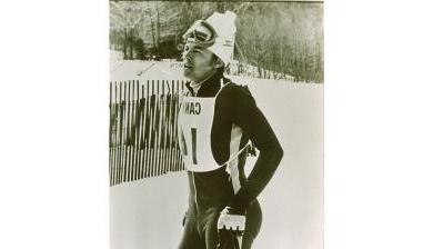 On a mountainside, Otto st和s with ski poles 和 a racing suit. 